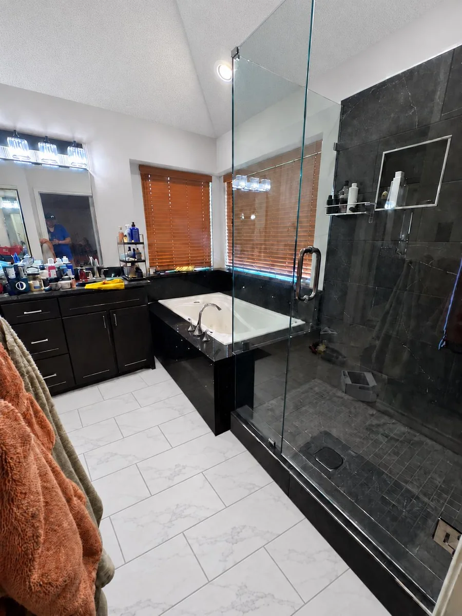 Completed Plano bathroom with a dark tiled shower, frameless glass, built-in tub surround and light tile floor