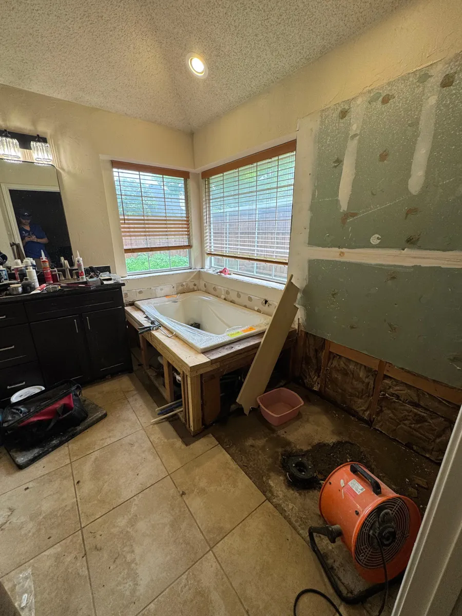 Plano bathroom during construction with the tub positioned in its framed surround and the adjoining shower area still unfinished